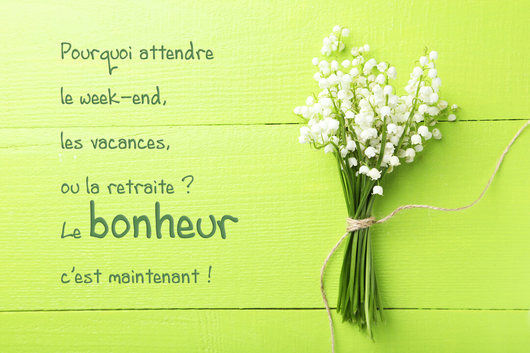 Un bouquet de muguet frais aux clochettes blanches, noué par une ficelle, est posé sur une surface en bois peinte en vert clair.