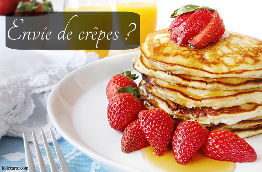 Une pile de pancakes dorés avec des fraises fraîches sur une assiette blanche, accompagnée de verres de jus d'orange en arrière-plan.