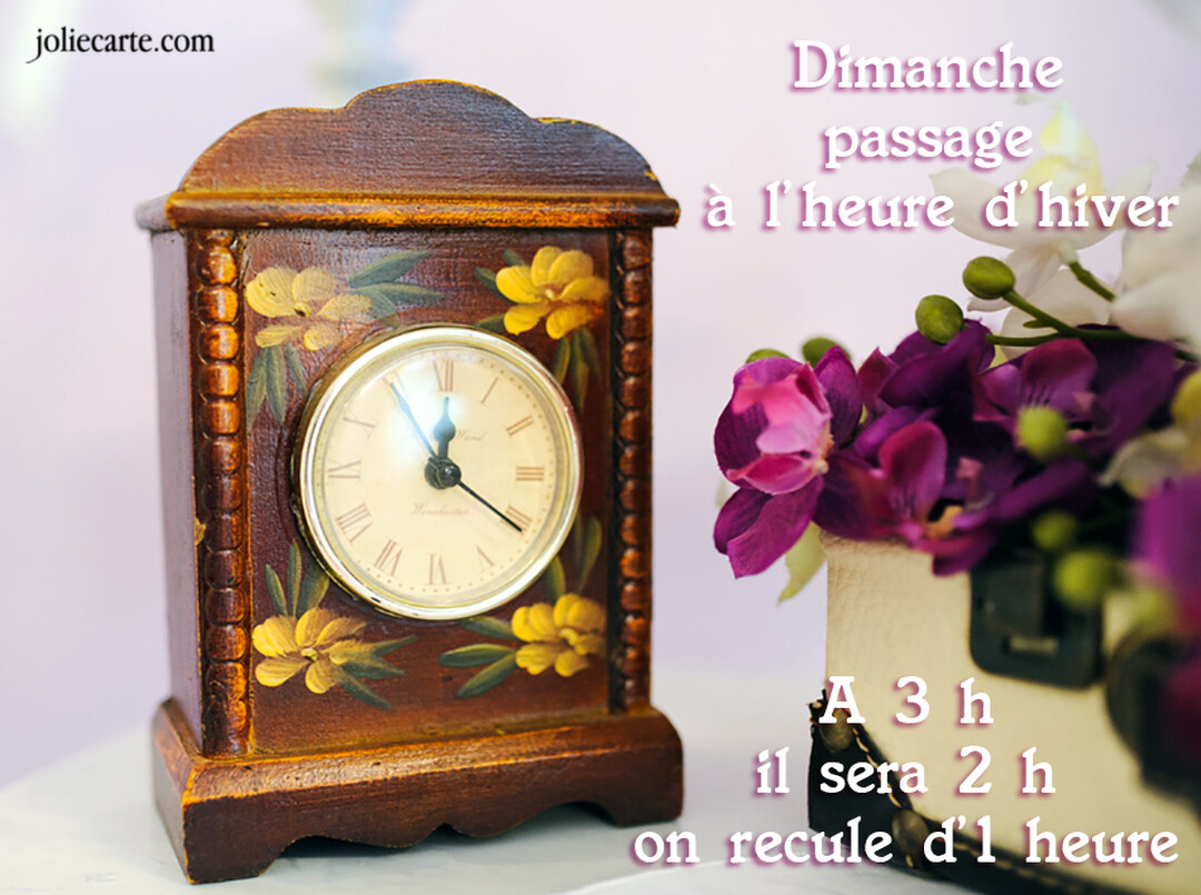 Une carte illustrée d'une horloge de cheminée en bois décorée de fleurs, avec un texte rappelant le passage à l'heure d'hiver.