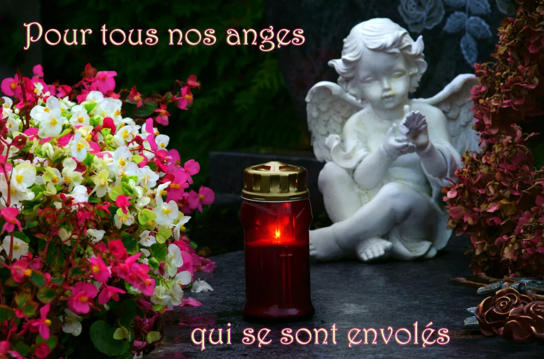 Sur une pierre tombale, une statue d'ange est assise près d'une bougie allumée et d'un bouquet de fleurs roses et blanches.