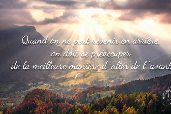 Paysage de montagne automnal avec rayons de soleil perçant les nuages et une citation sur l'importance d'aller de l'avant.