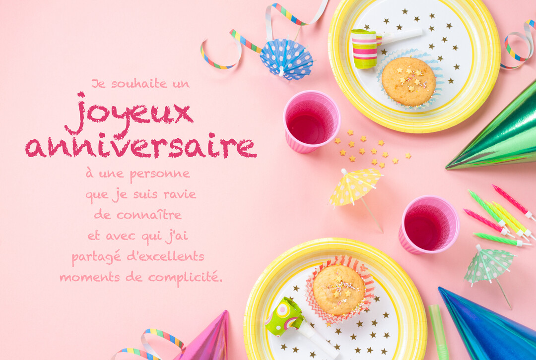 Une composition festive pour un anniversaire vue de dessus, avec des cupcakes, gobelets, chapeaux pointus et serpentins sur un fond rose uni.