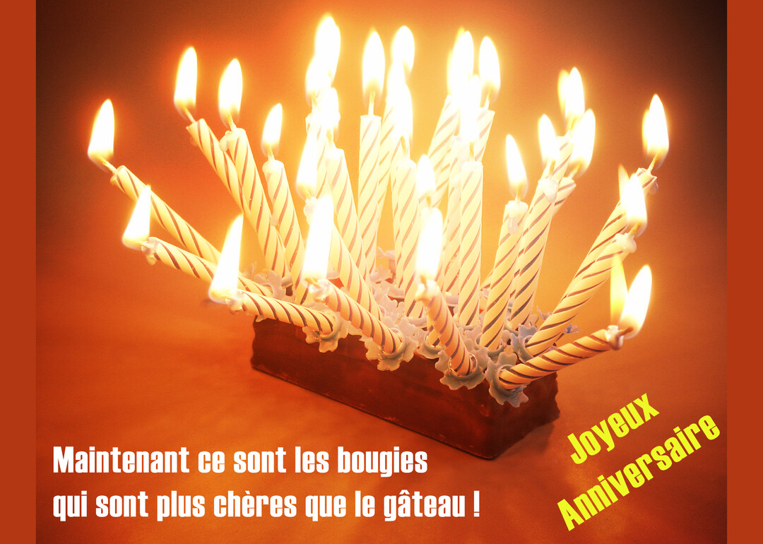 De multiples bougies d'anniversaire torsadées et allumées, plantées dans un support, illuminent la scène d'une lueur chaude sur un fond orangé.