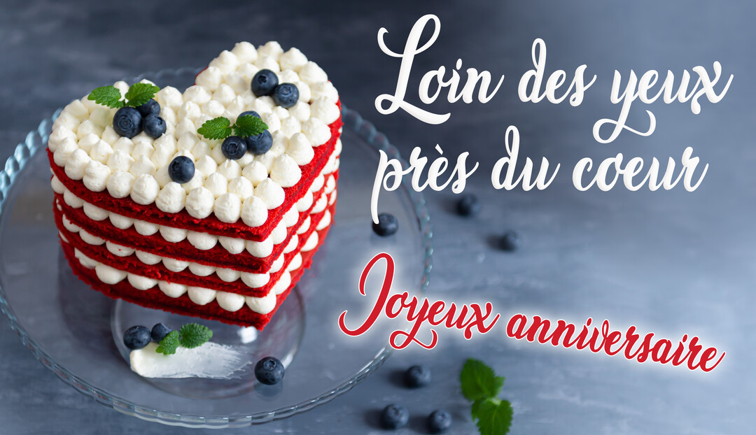 Un gâteau d'anniversaire rouge et blanc en forme de cœur, décoré de myrtilles, posé sur un plat en verre avec un fond gris.
