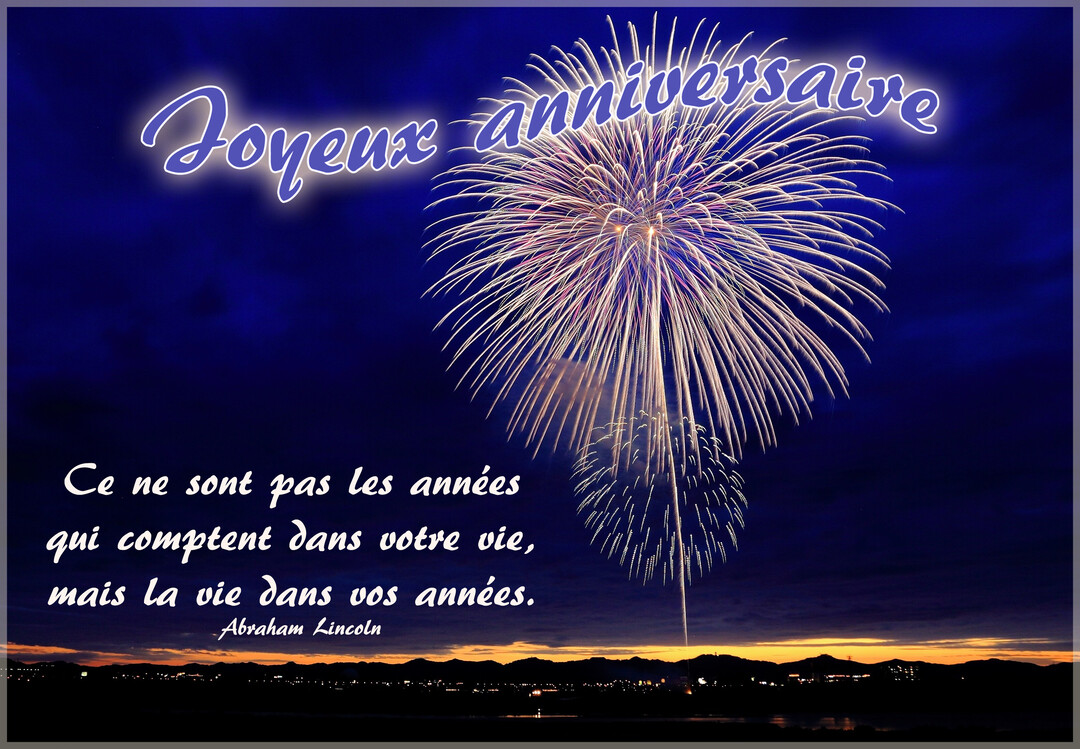 Un feu d'artifice blanc éclate dans un ciel nocturne au-dessus d'une ville, avec un message de joyeux anniversaire et une citation philosophique.