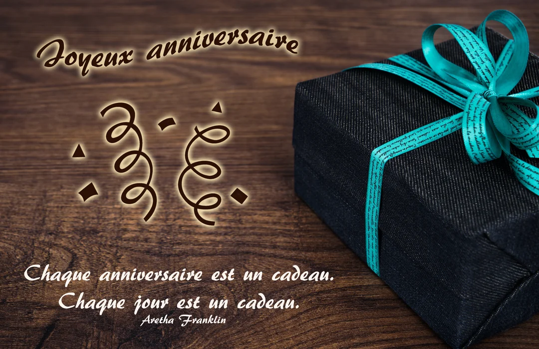 Une carte d'anniversaire présentant une boîte cadeau noire avec un ruban turquoise, posée sur une surface en bois à côté d'une citation lumineuse.