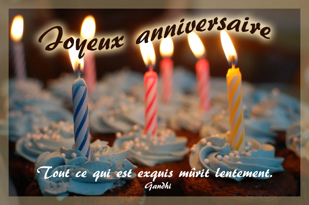 Un gros plan de cupcakes décorés de glaçage bleu et de bougies d'anniversaire multicolores allumées, créant une ambiance chaleureuse et festive.