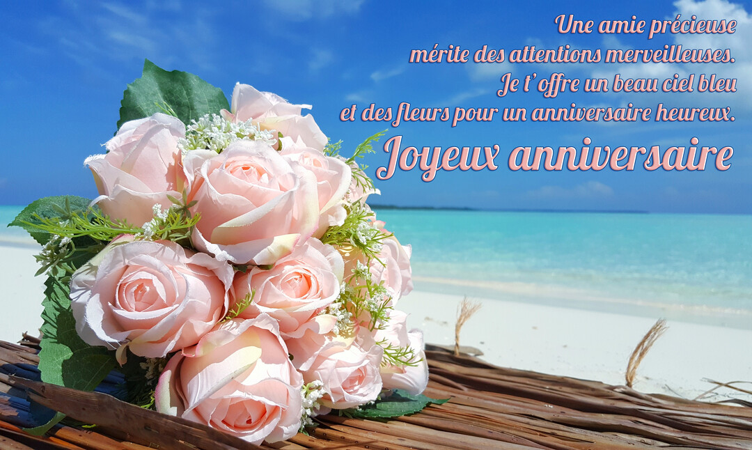 Un bouquet de roses roses repose sur du bois de palmier séché, avec en arrière-plan une plage tropicale et une mer turquoise.