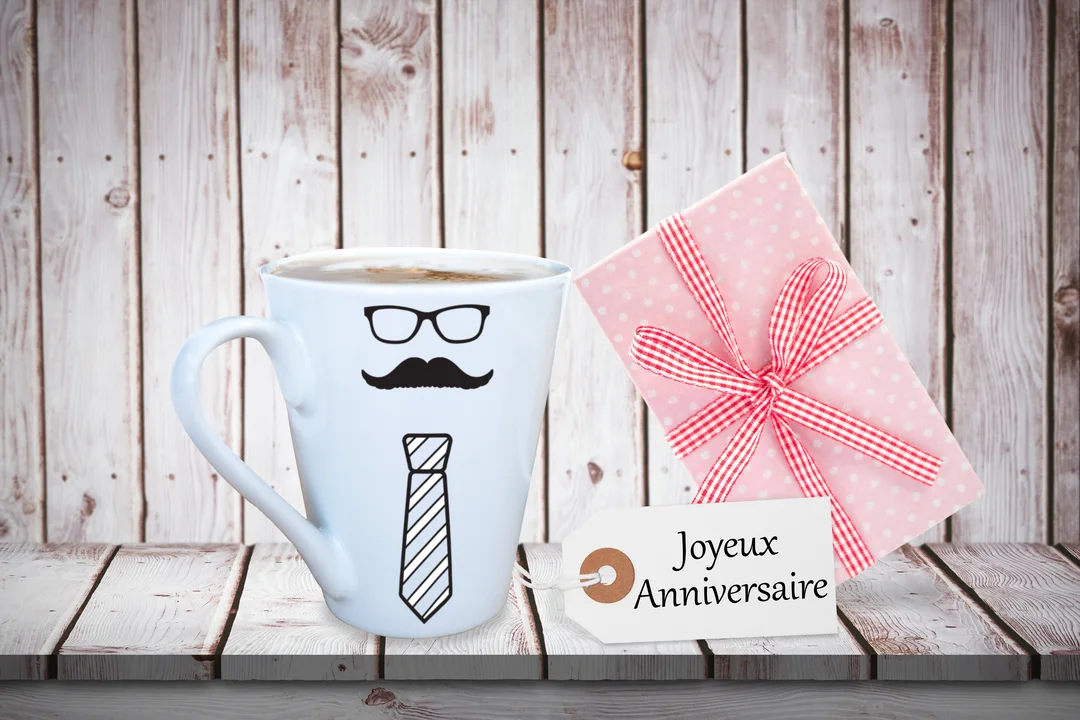 Une mise en scène d'anniversaire pour un papa, avec un mug-personnage, un cadeau et une étiquette 'Joyeux Anniversaire' sur fond en bois.