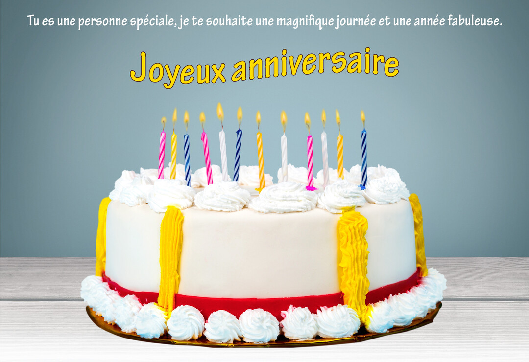 Un gâteau d'anniversaire rond avec un glaçage blanc, des décorations jaunes et rouges, et des bougies colorées allumées, posé sur une table en bois.