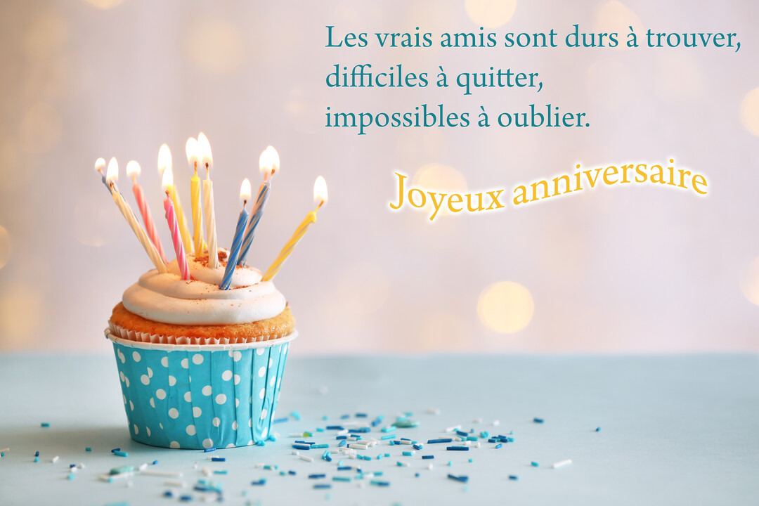 Un cupcake festif surmonté de bougies allumées, posé sur une surface bleue avec des vermicelles, devant un fond lumineux et flou.