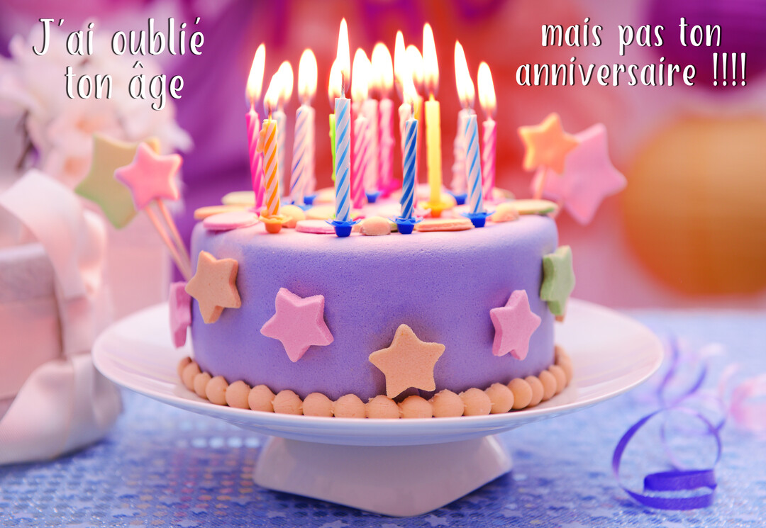 Un gâteau d'anniversaire violet orné d'étoiles et de nombreuses bougies colorées allumées, posé sur une table de fête scintillante.
