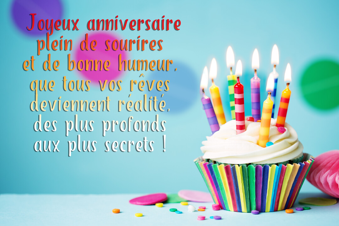 Un cupcake festif avec un glaçage blanc et des bougies multicolores allumées, posé sur une surface bleue avec des confettis éparpillés.