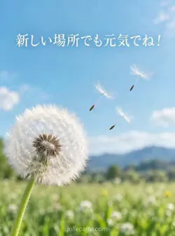 青緑の草原を背景に、左下のタンポポから三つの白い綿毛が空へ飛び立つ写真。